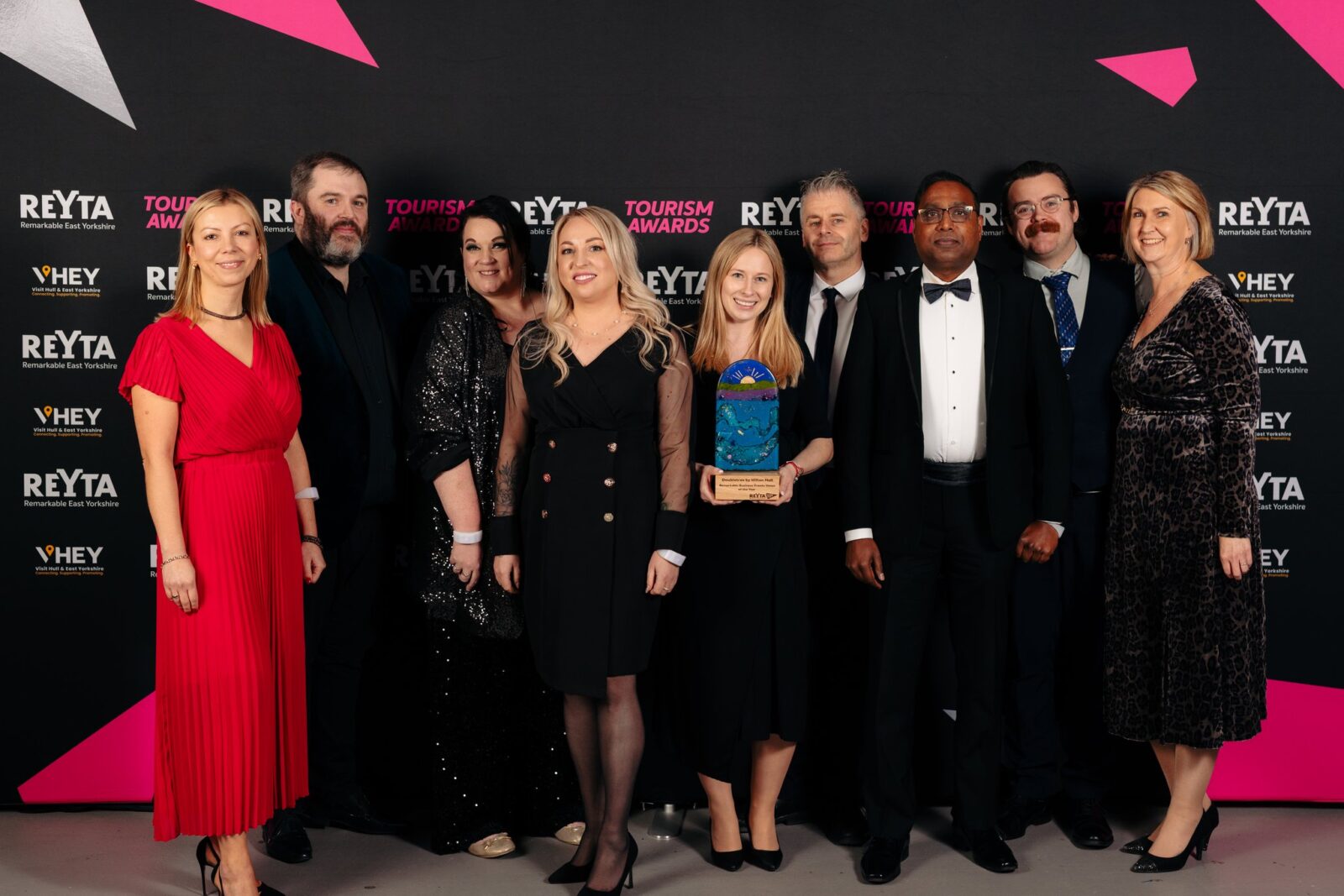 Group of people dressed in evening wear holding an award