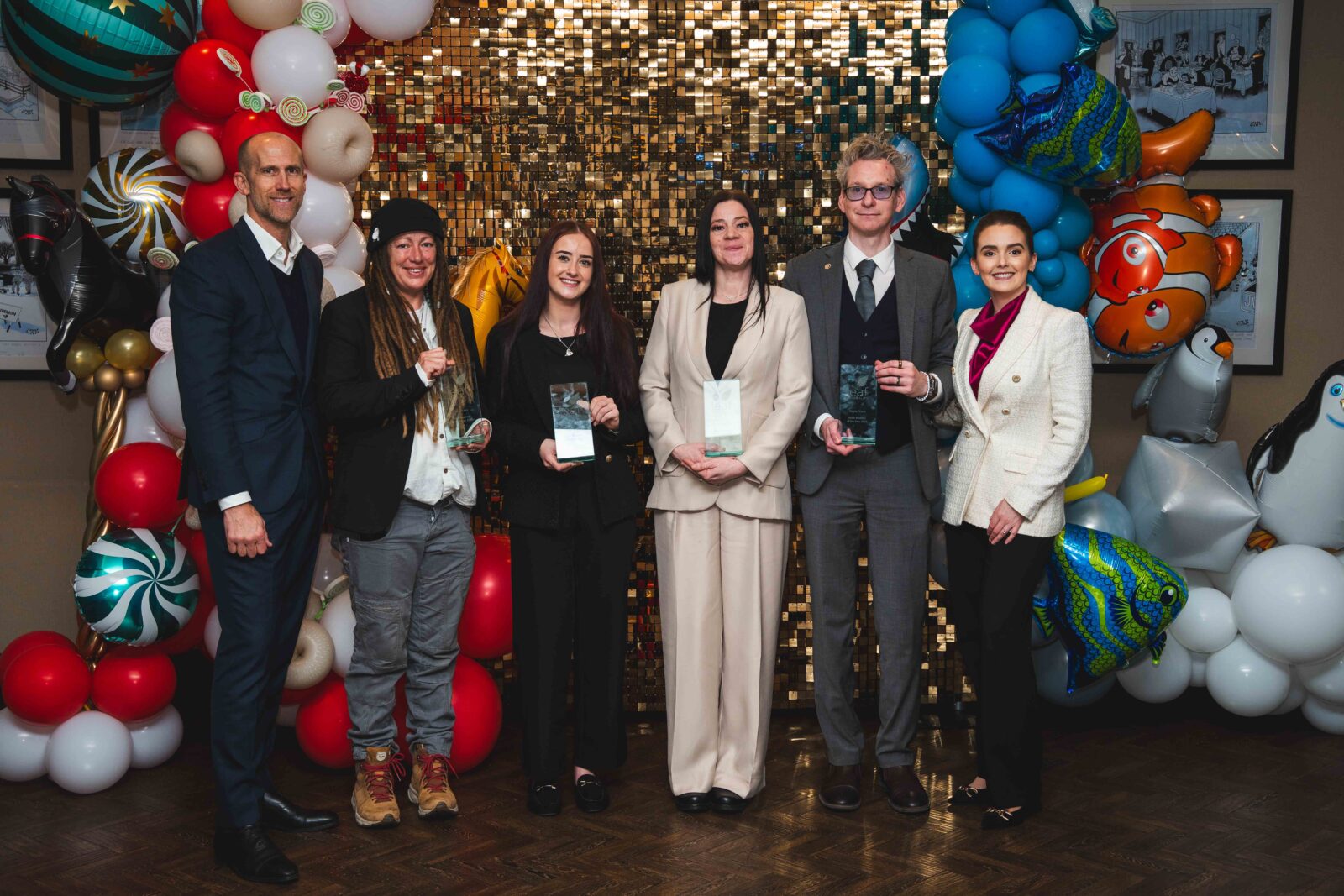 Group of people facing camera holding glass awards